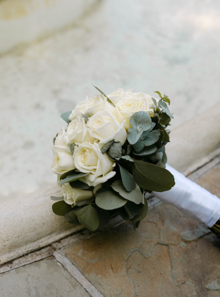 A Bride's simple white roses laid on a fountain for a detail photo prior to walking down the aisle