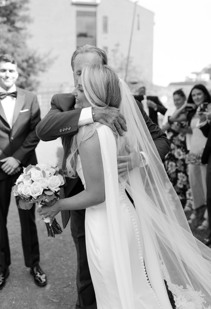 Father hugs the bride before giving her away to the groom on their wedding day