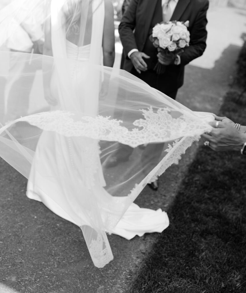 Maid of honor adjusts the veil before bride and groom say their vows