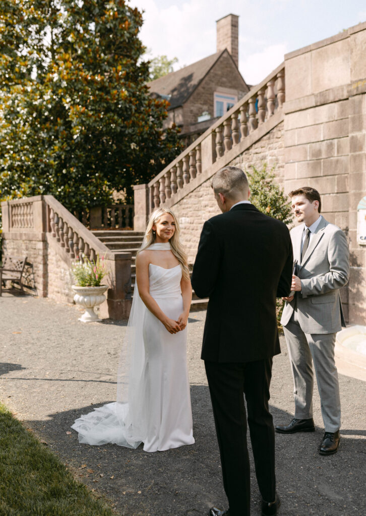 bride looks lovingly at the groom while he reads his vows to her