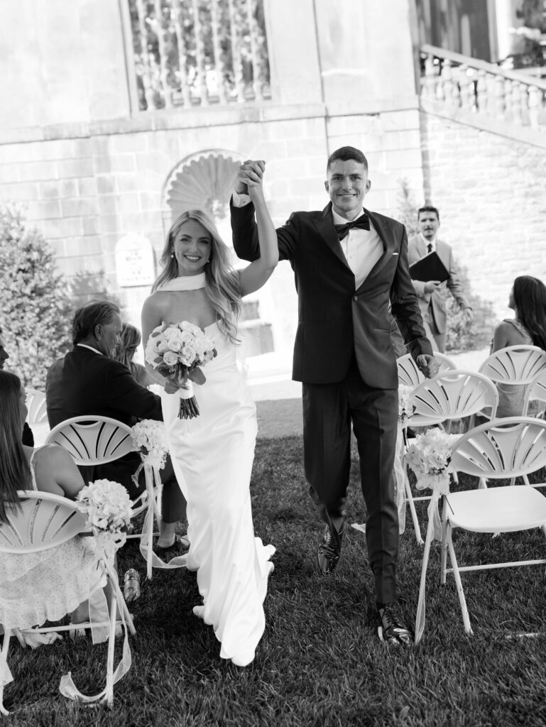 the bride and groom cheer while walking down the aisle as husband and wife