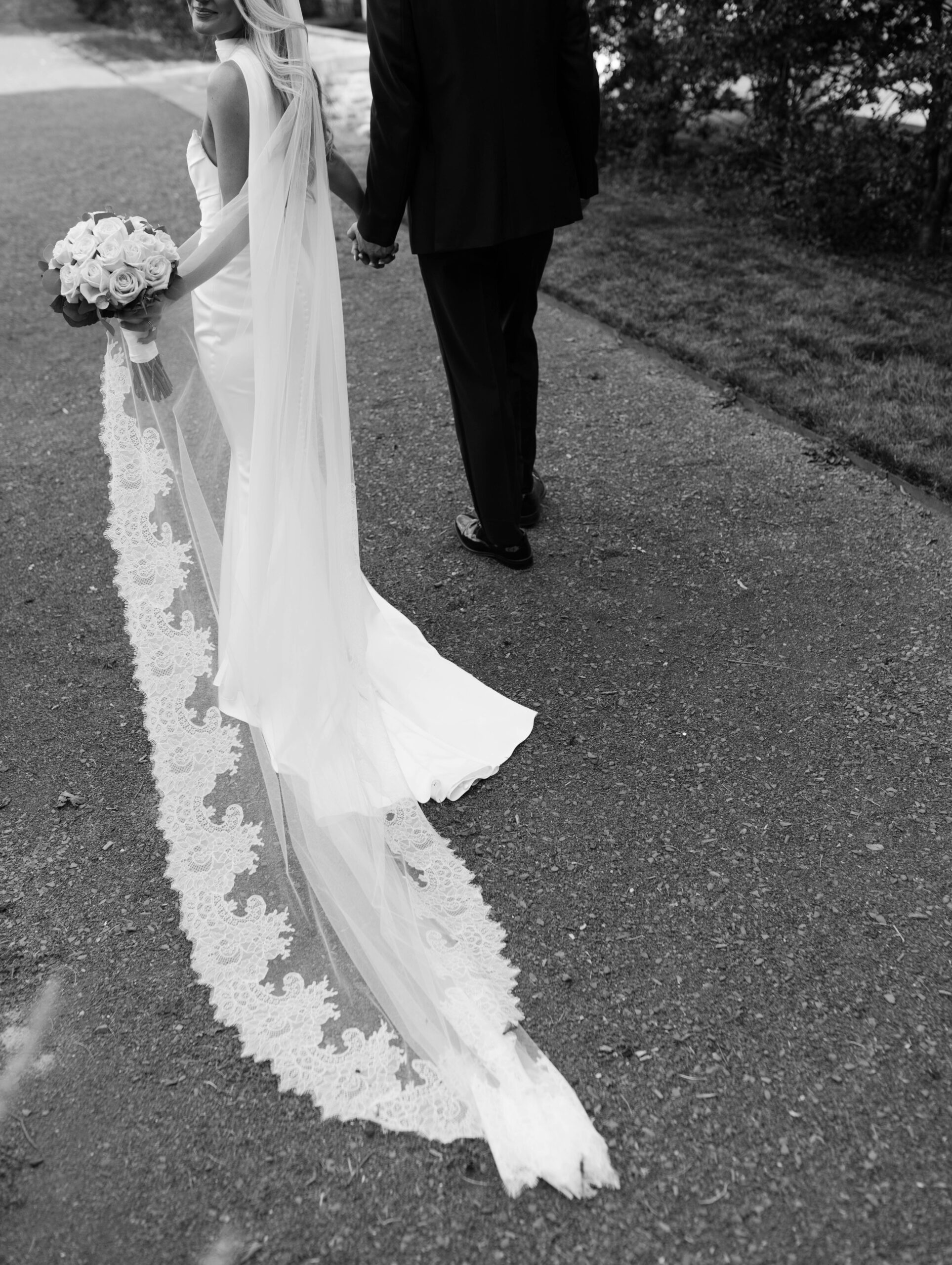 the bride and groom pose for portraits in a classic timeless white gown and black tuxedo in the lush gardens of Tyler Gardens