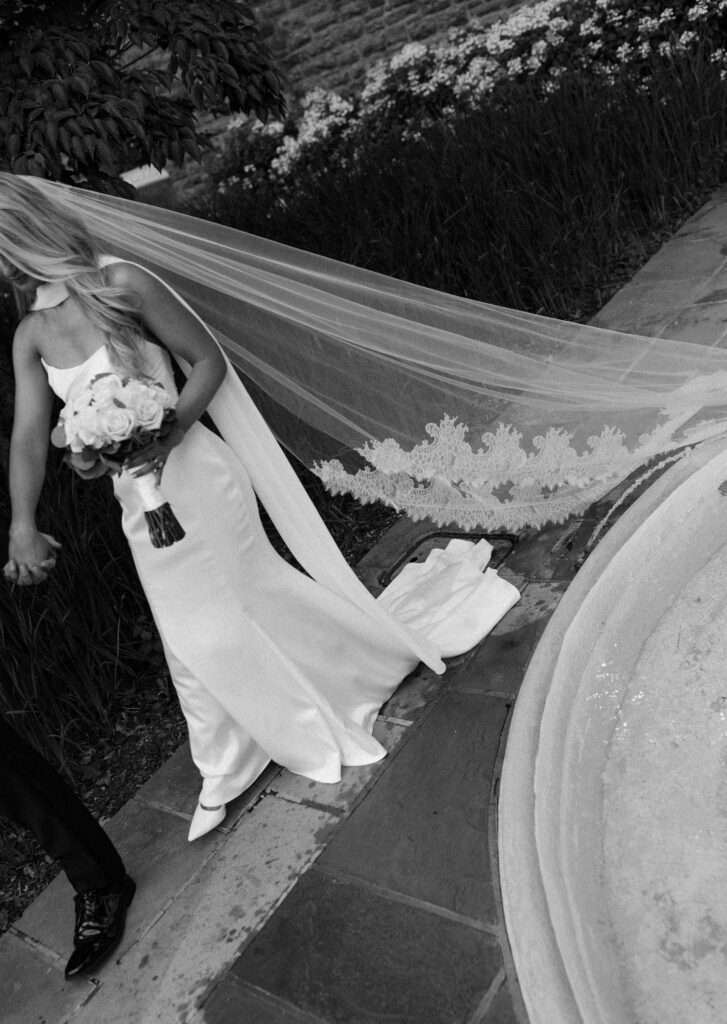 the bride and groom pose for portraits in a classic timeless white gown and black tuxedo in the lush gardens of Tyler Gardens