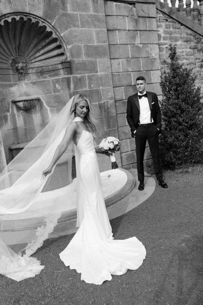 the bride and groom pose for portraits in a classic timeless white gown and black tuxedo in the lush gardens of Tyler Gardens