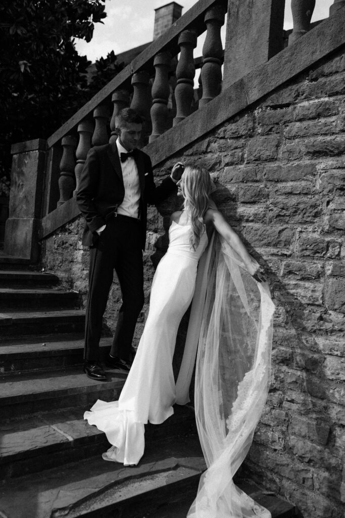 the bride and groom pose for portraits in a classic timeless white gown and black tuxedo in the lush gardens of Tyler Gardens