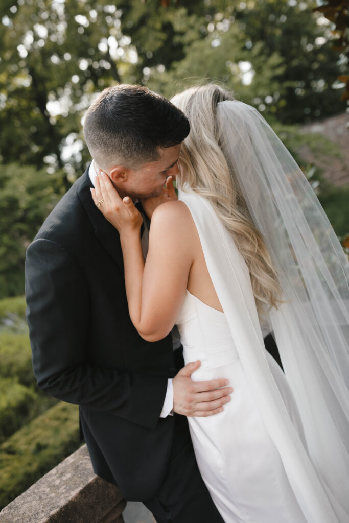 the bride and groom pose for portraits in a classic timeless white gown and black tuxedo in the lush gardens of Tyler Gardens