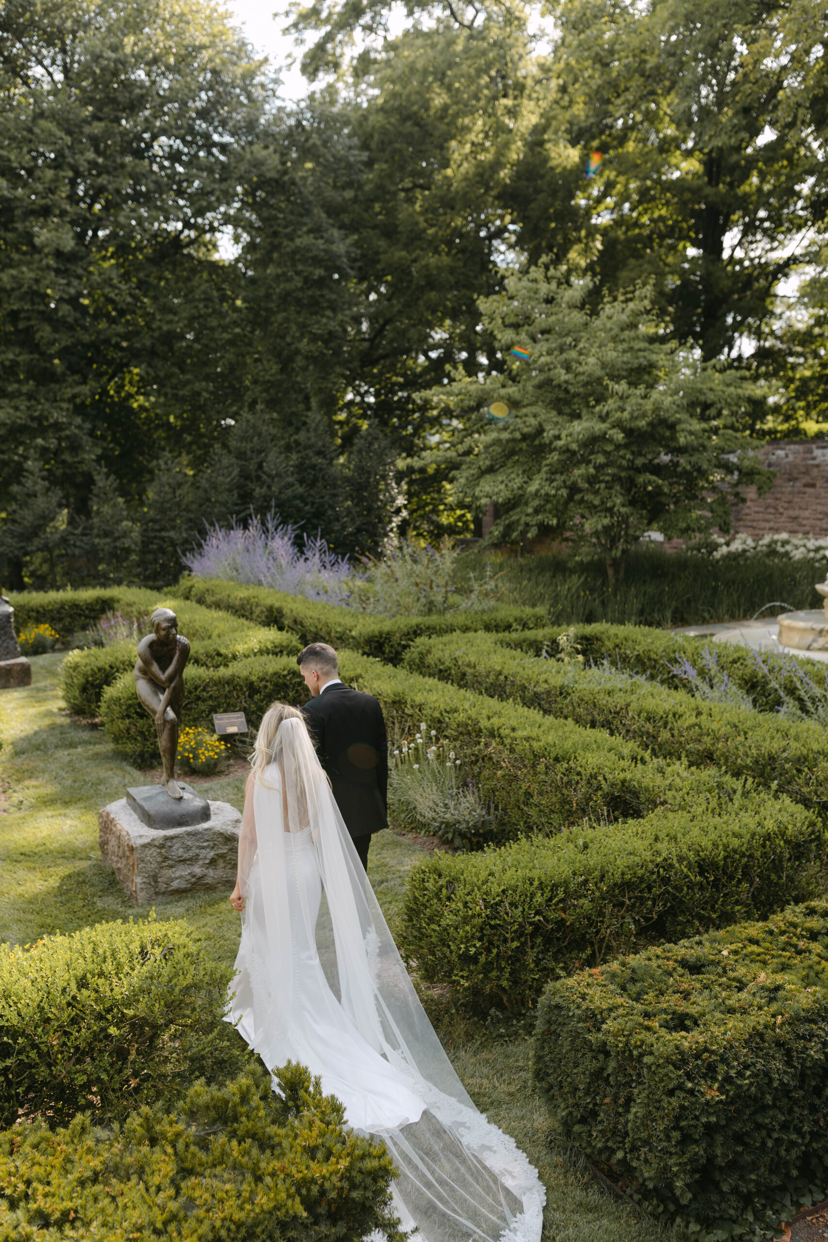 the bride and groom pose for portraits in a classic timeless white gown and black tuxedo in the lush gardens of Tyler Gardens